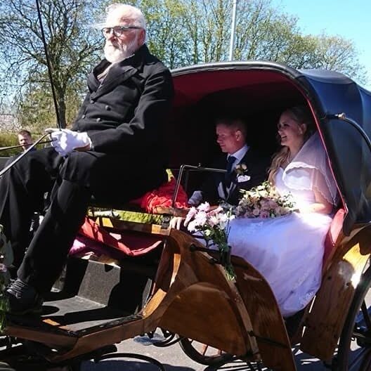 A bride and groom in a flower-decorated horse-drawn carriage with Ivan driving on Hven